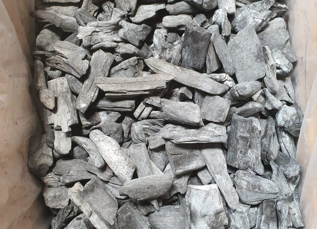 Mangrove lump charcoal pieces packed in a bag, showing the dense, ashy-grey surface